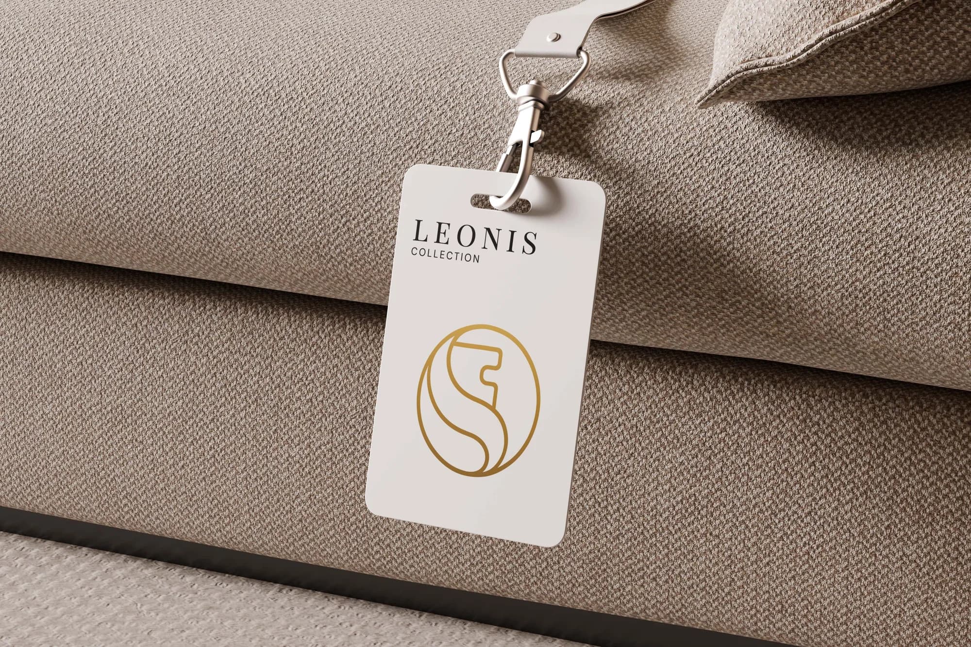 Luggage tag in ivory with the gold lion mark, resting on folded linen.